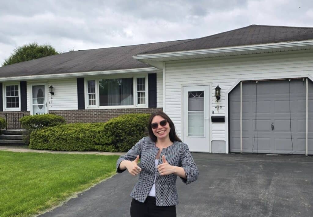 Happy homebuyer standing in front of a residential home after an inspection