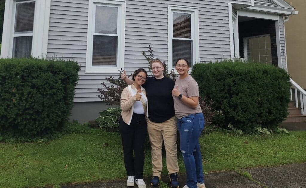 Three happy homebuyers standing outside a residential home after a home inspection